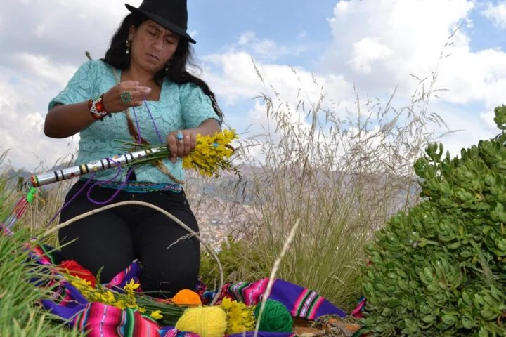 La lesbiana aymara Adriana Guzmán durante una sesión fotográfica del Movimiento Maricas Bolivia. Rodeada de elementos nativos y con un paisaje rural.