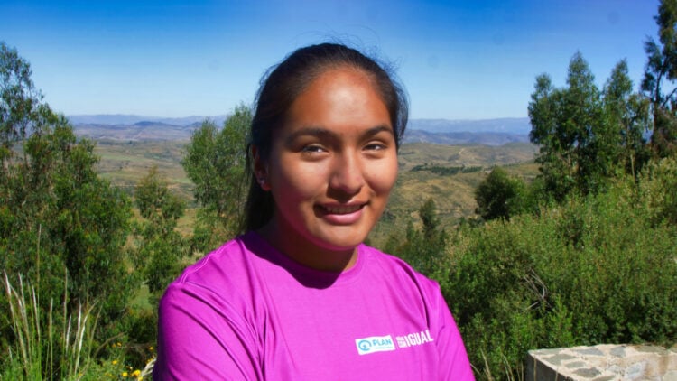 La lideresa quechua Virginia sonríe a la cámara con el paisaje de Tarabuco al fondo.