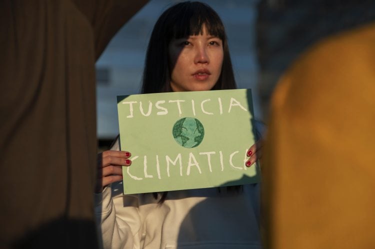 Activistas jóvenes sosteniendo un cartel sobre justicia climática.