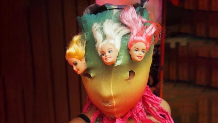 Imagen de una mujer con una máscara hecha con rostros de Barbie. Fotograma de la película Revolucion Put4 de Maria Galindo