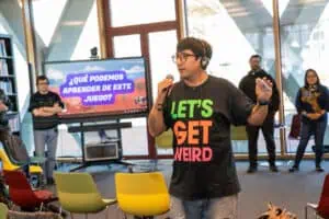 Mijail Miranda de pie con varias personas alrededor, hablando sobre la experiencia de gamificar estrategias contra la desinformación