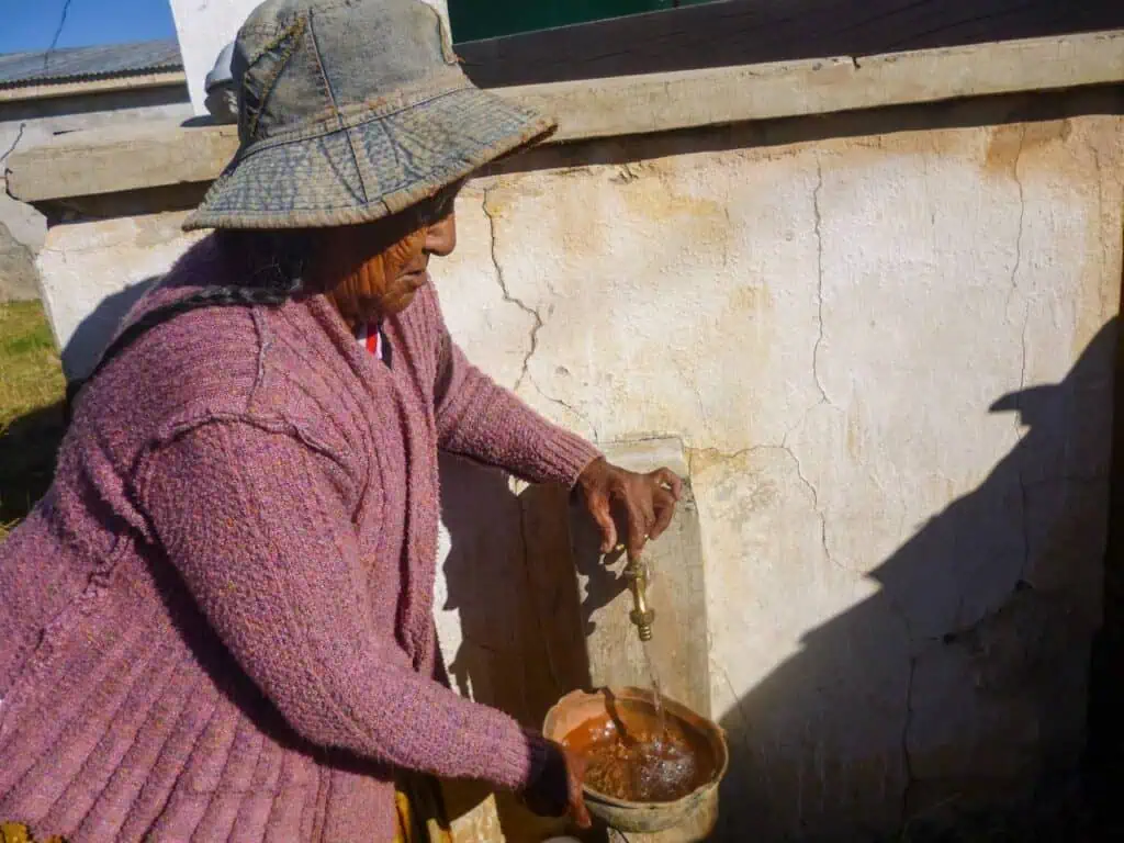 Una mujer anciana recibe agua en un pequeño cuenco en el altiplano boliviano.