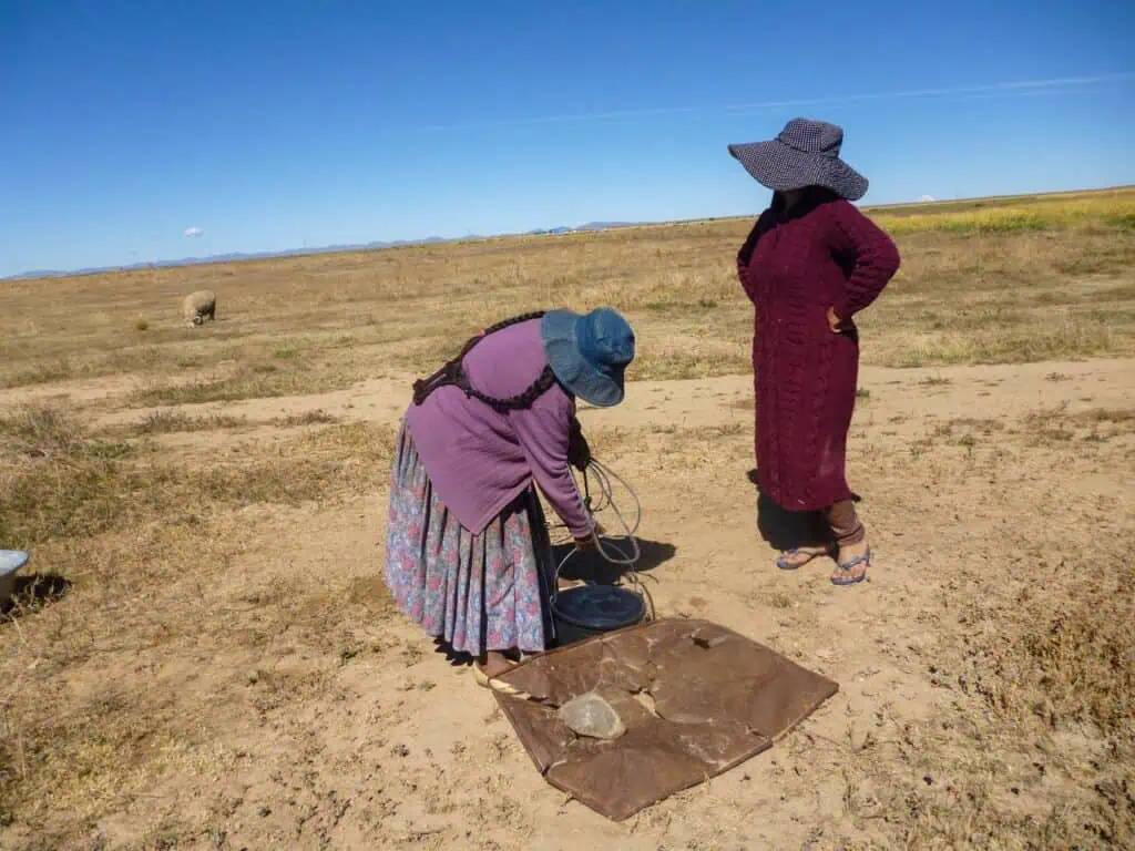 Dos mujeres sacan agua de un pozo en medio del altiplano boliviano. 