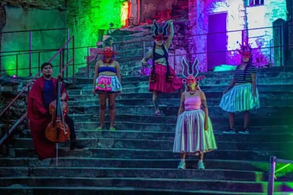 Cholitas da Babilonia durante una performance artística, en unas grdas, con trajes típicos bolivianos intervenidos artísticamente..